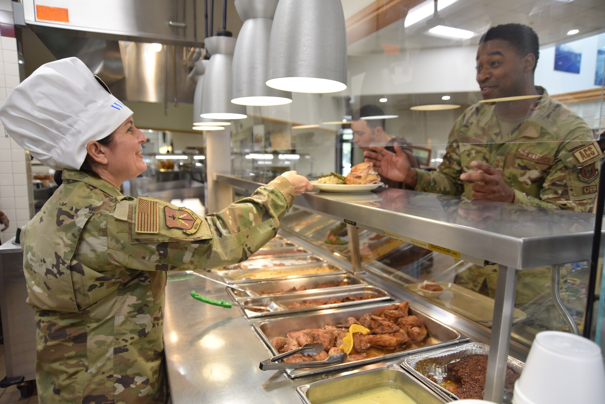 Chief Master Sgt. Barbara J. Gilmore hands a plate of food to an Airman.