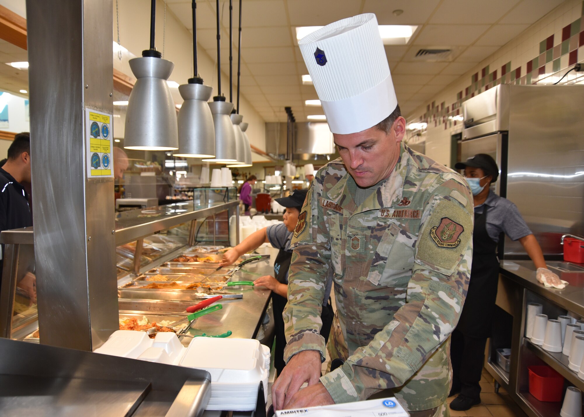 Chief Master Sgt. Tommy Lassabe reaches for plates to serve lunch.