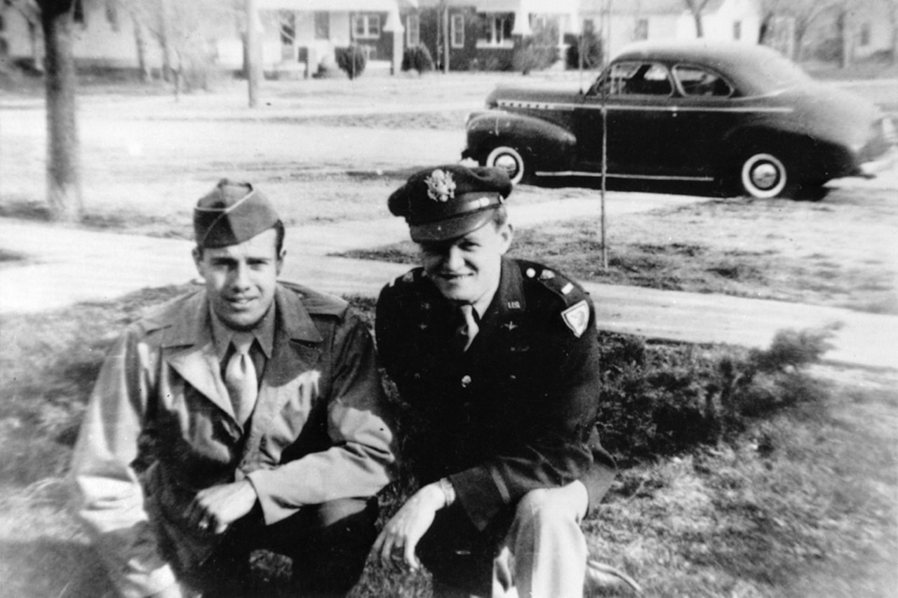 Two men kneel and pose for a photo.