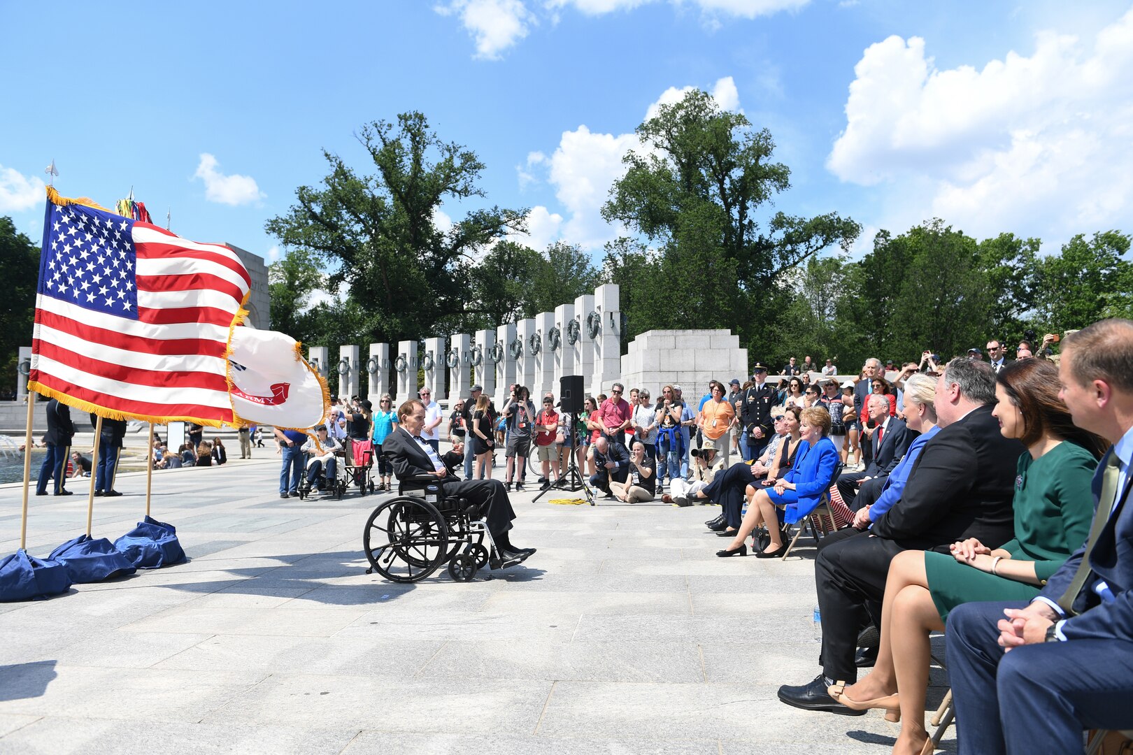 Wide-angle view of a man in a wheelchair facing a crowd at the National World War II Memorial.
