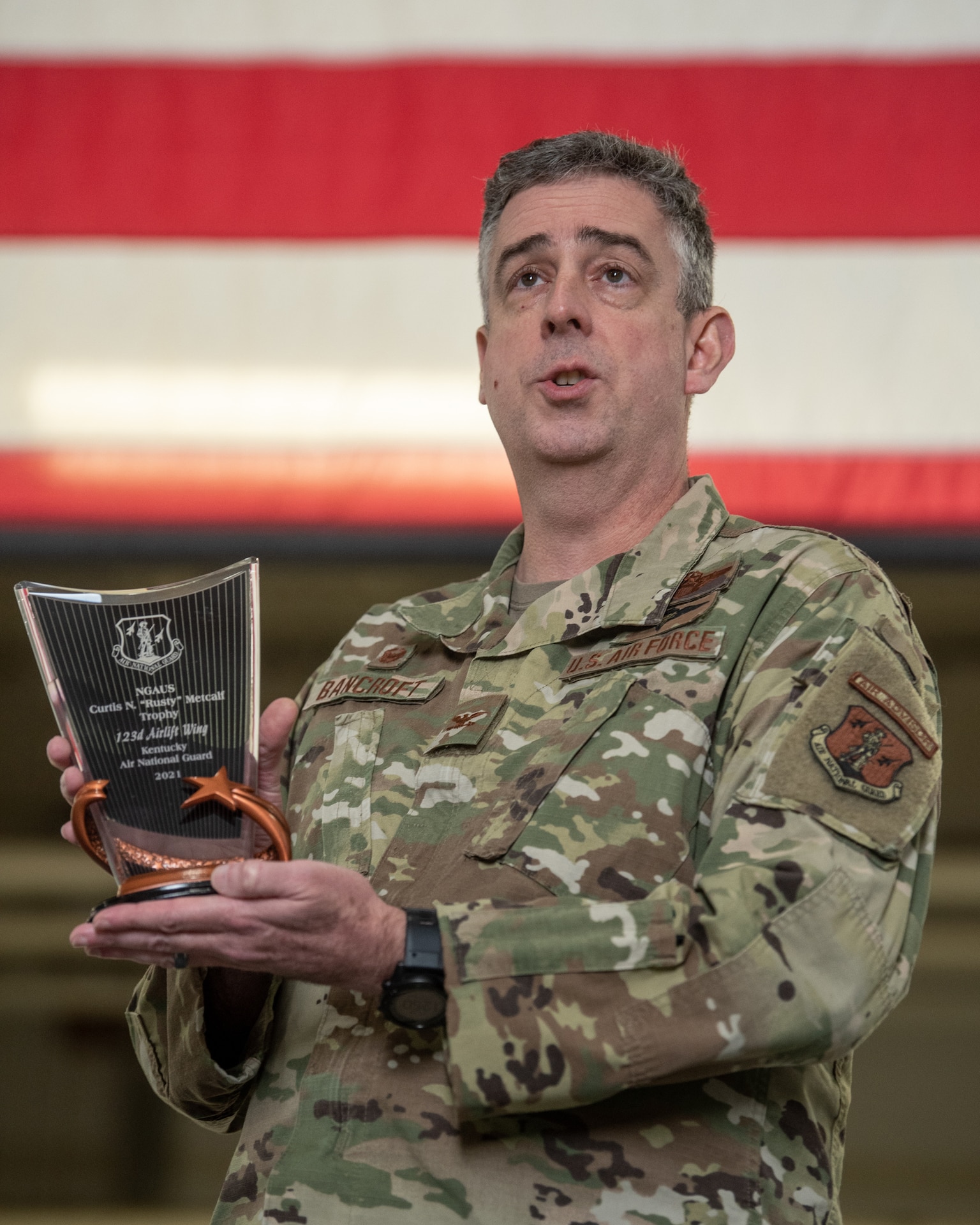 Col. Bruce Bancroft, commander of the 123rd Airlift Wing, speaks to hundreds of Air Guardsmen during a ceremony celebrating the wing’s fifth Curtis N. “Rusty” Metcalf Trophy at the Kentucky Air National Guard Base in Louisville, Ky., Dec. 5, 2021. Bestowed annually by the National Guard Association of the United States, the trophy recognizes the airlift or air refueling unit that demonstrates the highest standards of mission accomplishment. (U.S. Air National Guard photo by Tech. Sgt. Joshua Horton)