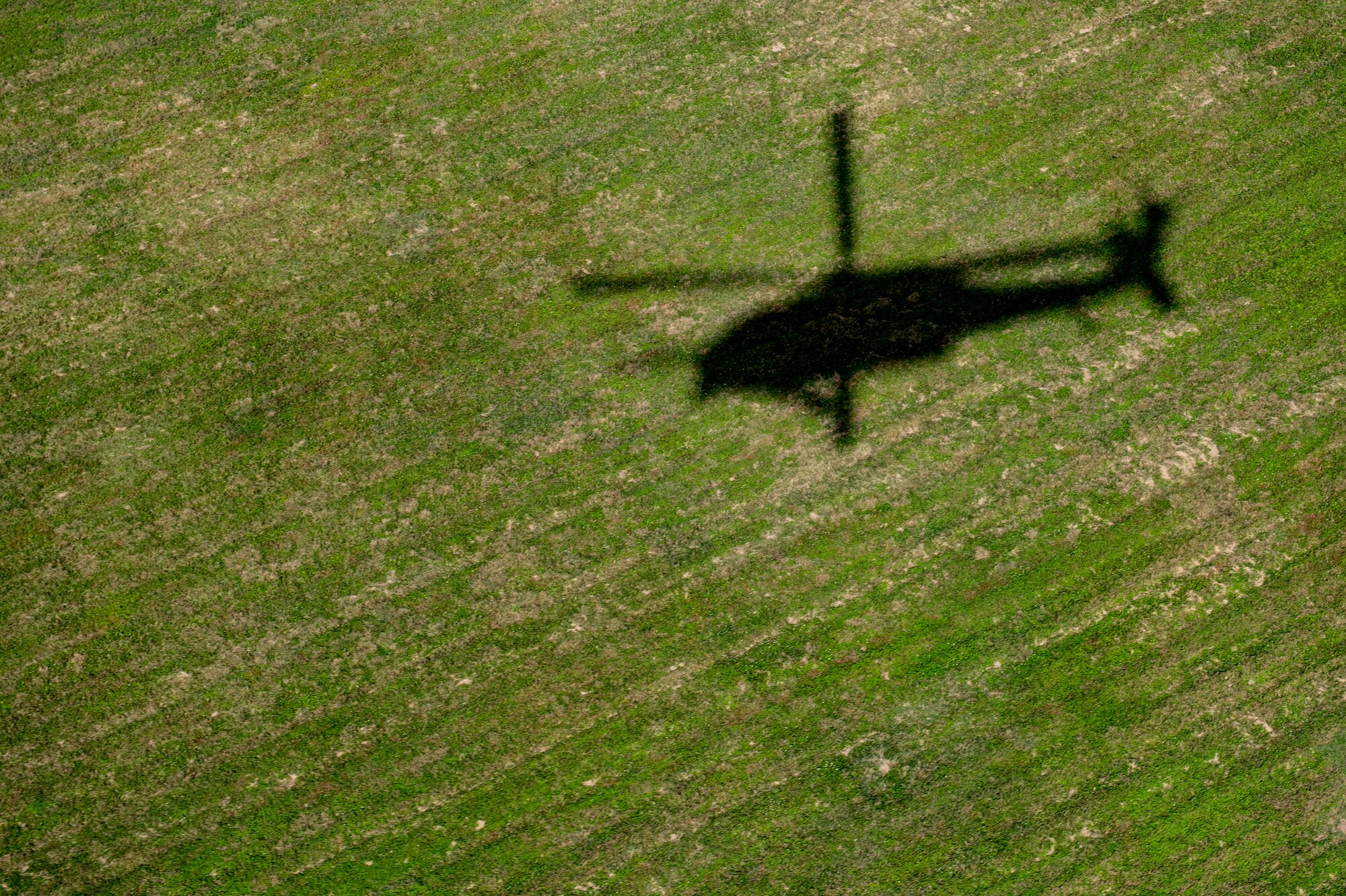 A shadow is cast by an HH-60G Pave Hawk assigned to the 33rd Rescue Squadron as it takes off from Kadena Air Base, Japan, Dec. 1, 2021. The 33rd RQS plays a vital role in the Indo-Pacific region providing search, rescue and recovery mission capabilities. (U.S. Air Force photo by Senior Airman Jessi Monte)