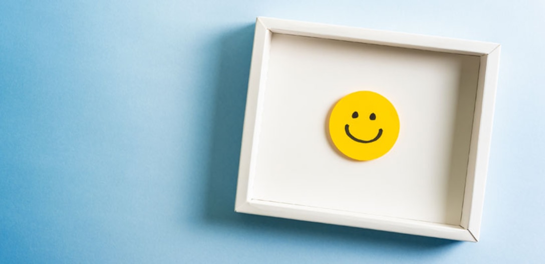 Yellow happy face in a white box on a blue background