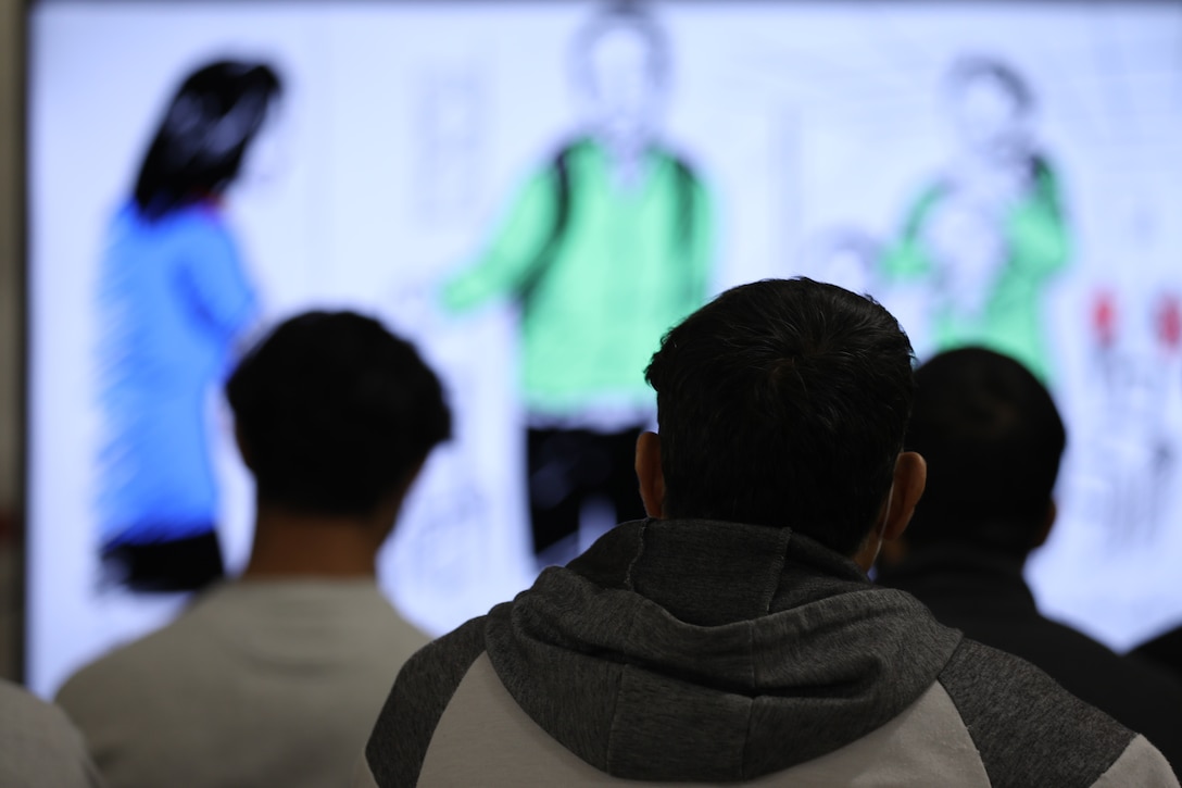 Afghan evacuees watch a video on American customs in a resettlement class.