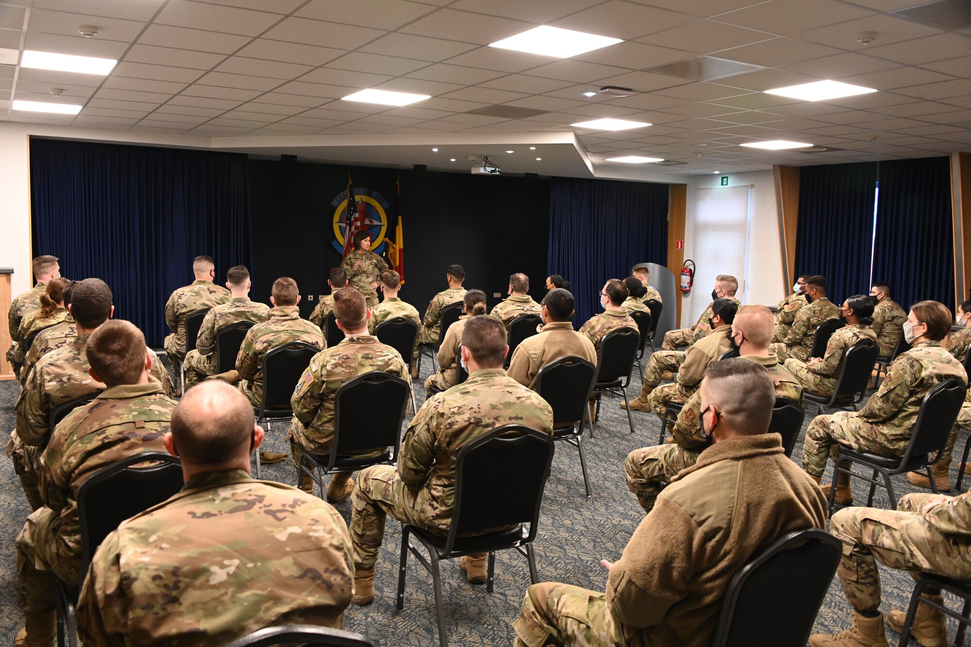 Chief Master Sgt. of the Air Force JoAnne S. Bass speaks in front of Airmen 52nd Fighter Wing Airmen, Dec. 2, 2021, on Spangdahlem Air Base, Germany. During her time at the 52nd Fighter Wing, Bass hosted an all-call, where she spoke about the strategic direction of the Air Force and provided an environment for Airmen to ask questions. (U.S. Air Force photo by Staff Sgt. Chanceler Nardone)