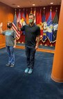 Man standing with is right arm raised in front of all military branch flags taking his Oath of Enlistment to join the United State Army.