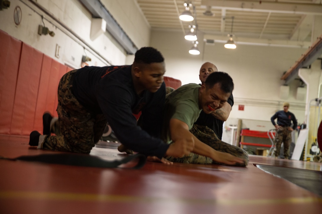 U.S. Marine Corps Sgt. Jason Aquino, a rifleman with 4th Bravo Company, Marine Corps Security Cooperation Group, Marine Corps Security Force Regiment, grapples against multiple Martial Arts Instructor Trainers during the Martial Arts Instructor (MAI) Course 101-22 cumulative event at Naval Weapons Station, Yorktown, Virginia, Nov. 5, 2021. The MAI course is a multifaceted course incorporating Marine Corps Martial Arts Program (MCMAP) techniques and teaching warrior ethos. Upon completion, Marines are awarded belt advancement and accredited to teach and certify Marines in close-quarters combat tactics, weapons of opportunity and other various MCMAP tactics. (U.S. Marine Corps photo by Lance Cpl. Angel Alvarado)