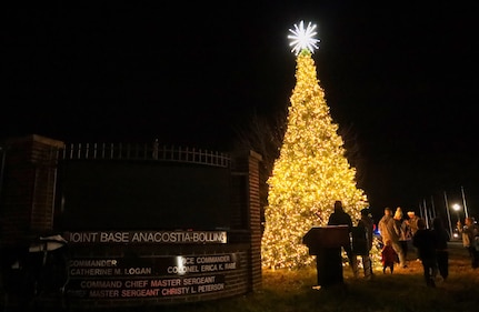 Families pose for pictures in front of the newly lit Christmas tree after the annual tree lighting ceremony on Joint Base Anacostia-Bolling, Washington D.C., Dec. 3, 2021. The tree-lighting ceremony marked the beginning of the holiday season at the installation. (U.S. Air Force photo by Brian Nestor)