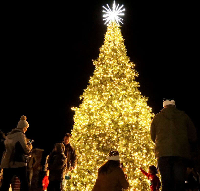 Families pose for pictures in front of the newly lit Christmas tree after the annual tree lighting ceremony on Joint Base Anacostia-Bolling, Washington D.C., Dec. 3, 2021. The tree-lighting ceremony marked the beginning of the holiday season at the installation. (U.S. Air Force photo by Brian Nestor)