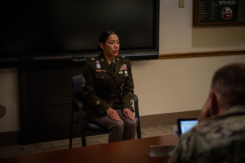 Female Soldier sitting in front of board members.