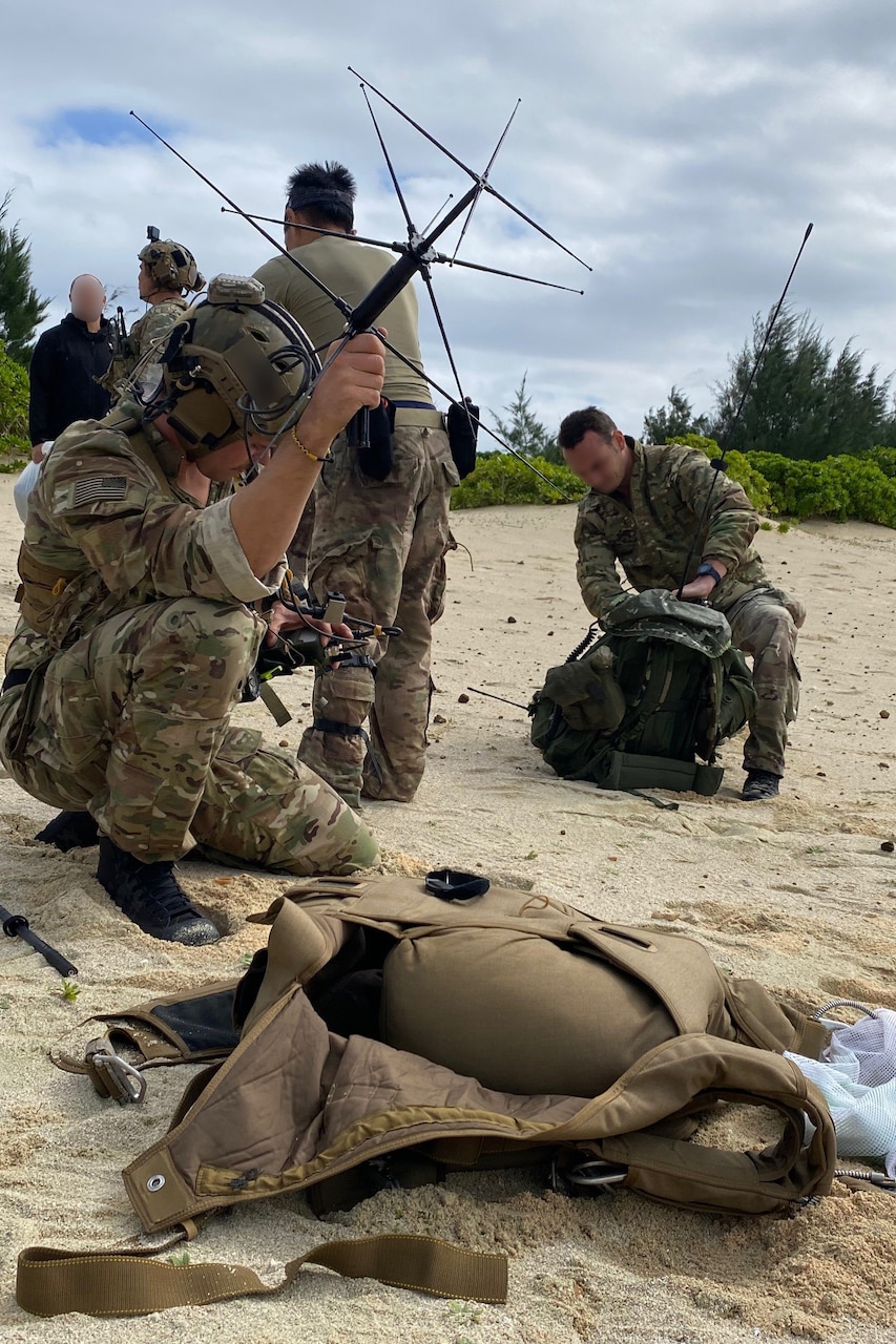 Soldiers set up radio satellites on sand.