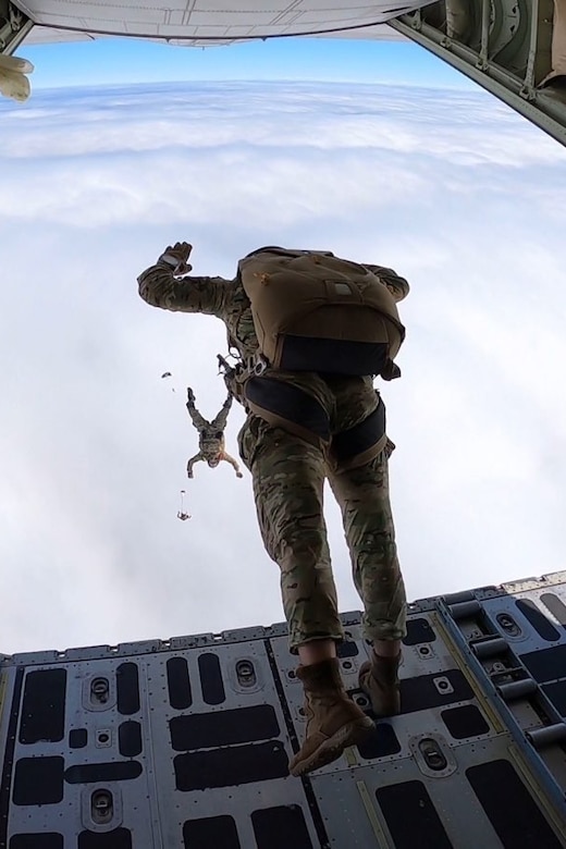 Soldiers jump out of an aircraft.
