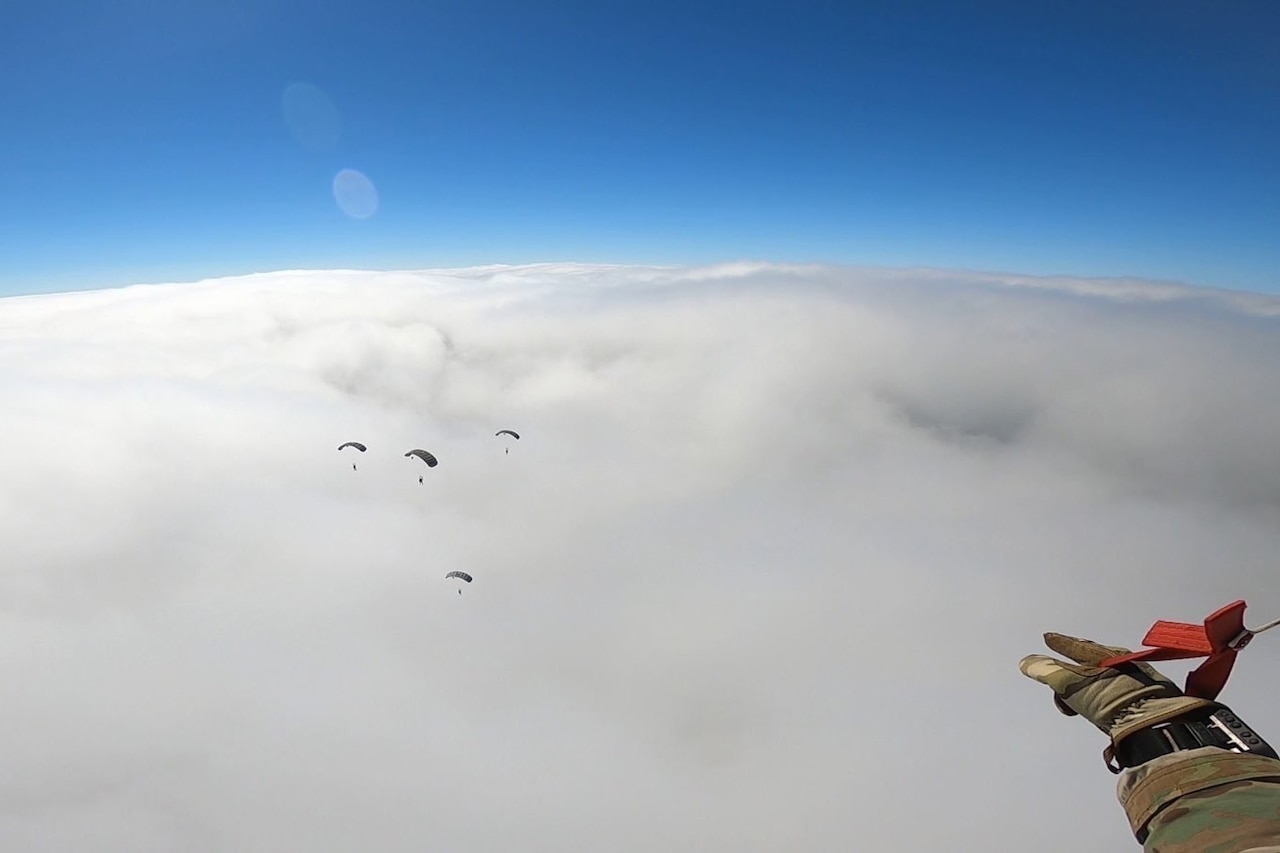 Soldiers freefall with parachutes.