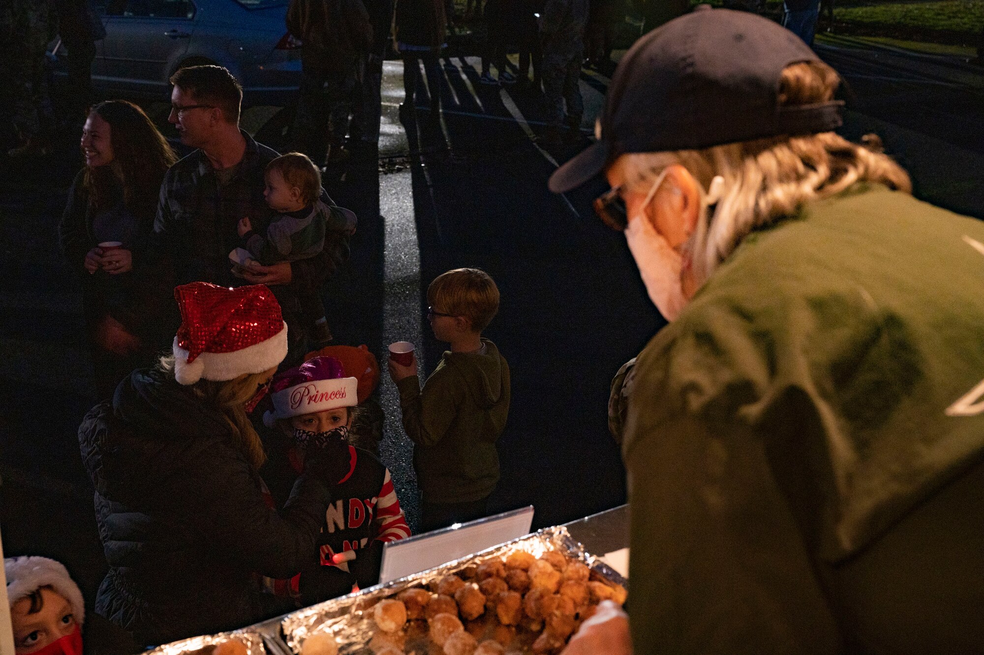 USO volunteers serve U.S. service members and their families during a tree lighting ceremony at Joint Base Lewis-McChord, Washington, Dec. 2, 2021. The volunteers spent their night at McChord Field giving out free refreshments to the attendees. (U.S. Air photo by Airman First Class Charles Casner)