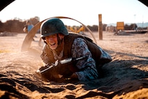 U.S. Marine Corps Recruit Zach Volpe with Mike Company, 3rd Recruit Training Battalion, crawls through and obstacle during a bayonet assault course at Marine Corps Recruit Depot San Diego, Nov. 23, 2021.