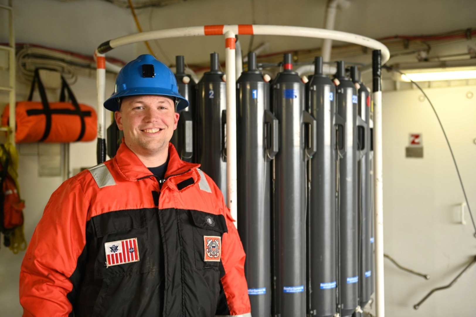 Coast Guard servicemember smiling next to scientific instruments on board Cutter Healy