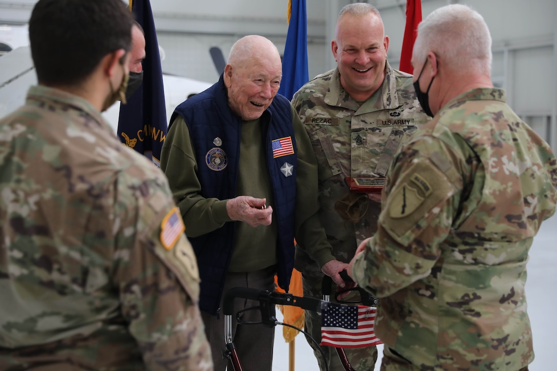 Sayre Christian Village resident Paul Frederick and Command Sgt. Maj. Paul Rezac, 63rd TAB, smile as Kentucky National Guard Adjutant General, Maj. Gen. Hal Lamberton presents Fredrick and Soldiers with a military coin for appreciation following a ceremony at the Army Aviation Support Facility hanger on Boone National Guard Center Dec. 2. The Soldiers are awarded the honors because of the assistance they provided during the pandemic. (US Army National Guard Photo by Mrs. Jesse Elbouab)