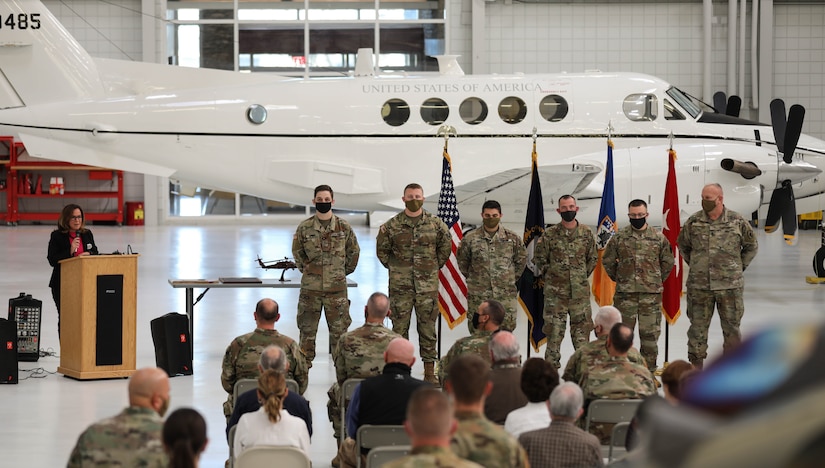 Karen L. Venis, Chief Executive Officer for Sayre Christian Village speaks about the six service members from the 63rd Theater Aviation Brigade stand while receiving the LeadingAge Kentucky Distinguished Service Award and the Guardian Angel Award during a ceremony at the Army Aviation Support Facility hanger on Boone National Guard Center Dec. 2. The Soldiers are awarded the honors because of the assistance they provided during the pandemic. (US Army National Guard Photo by Mrs. Jesse Elbouab)