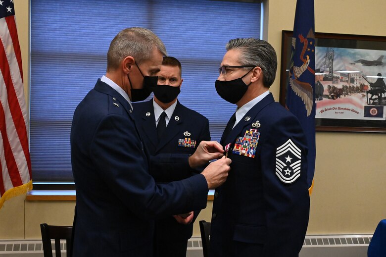 Brig. Gen. Darrin Anderson, the North Dakota National Guard assistant adjutant general for Air, places the Meritorious Service Medal on the jacket of Chief Master Sgt. Duane Kangas, the North Dakota Air National Guard state command chief, during his retirement ceremony at the North Dakota Air National Guard Base, Fargo, N.D., Dec. 4, 2021.