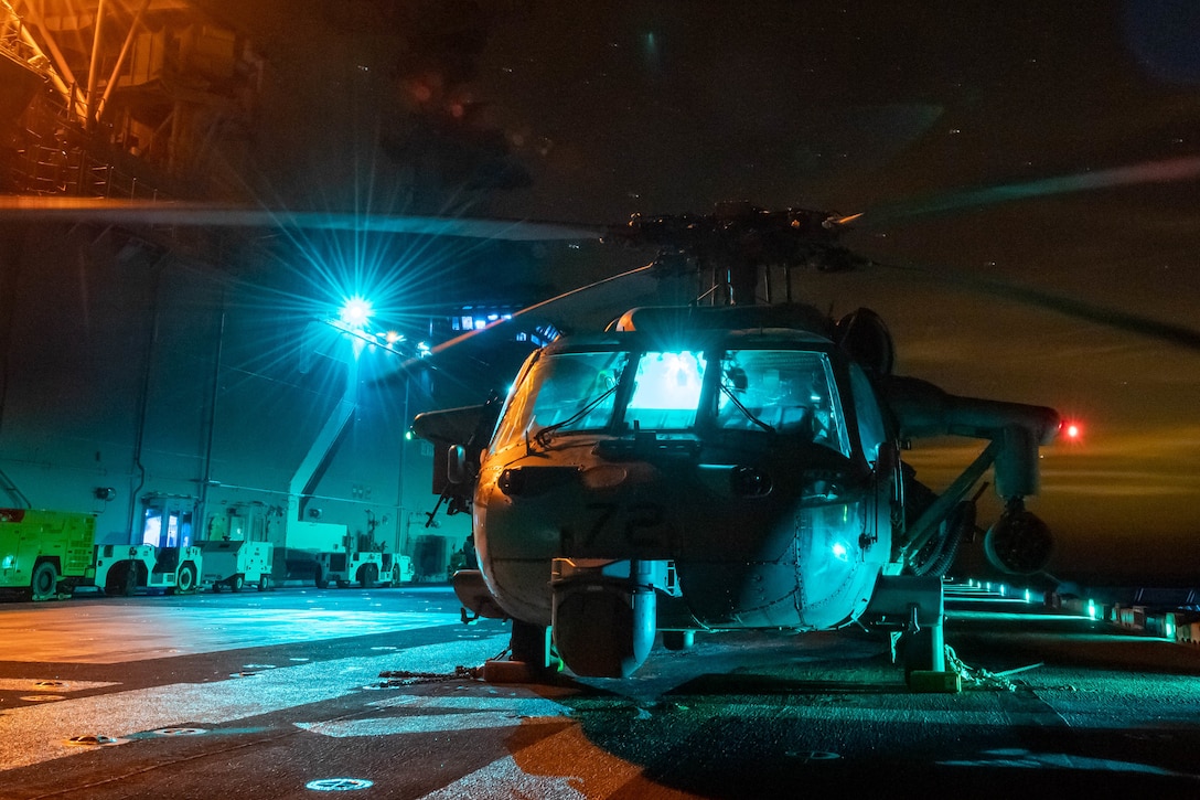 ARABIAN GULF (Dec. 4, 2021) MH-60S Sea Hawk helicopter, attached to Helicopter Sea Combat Squadron 21, is parked on the flight deck of the amphibious assault ship USS Essex (LHD 2) during night flight operations, Dec. 4. Essex and the 11th Marine Expeditionary Unit are deployed to the U.S. 5th Fleet area of operations in support of naval operations to ensure maritime stability and security in the Central Region, connecting the Mediterranean and the Pacific through the western Indian Ocean and three strategic choke points. (U.S. Navy photo by Mass Communication Specialist 2nd Class Brett McMinoway)