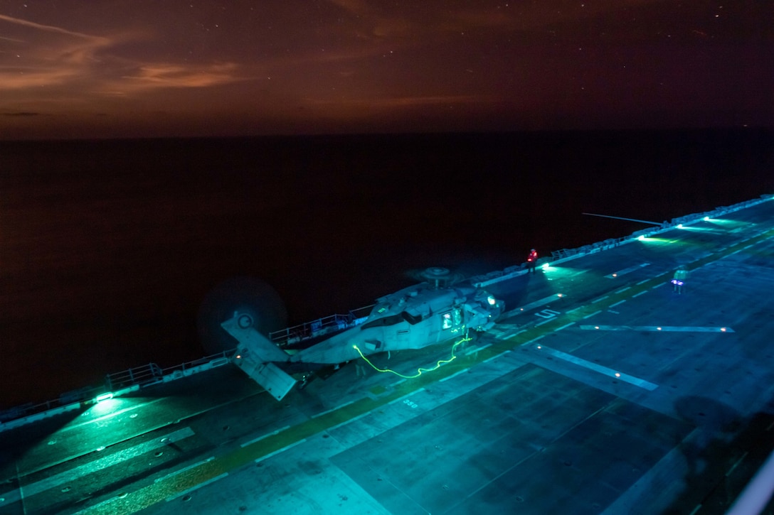 ARABIAN GULF (Dec. 4, 2021) MH-60S Sea Hawk helicopter, attached to Helicopter Sea Combat Squadron 21, prepares to takeoff from the flight deck of the amphibious assault ship USS Essex (LHD 2) during night flight operations, Dec. 4. Essex and the 11th Marine Expeditionary Unit are deployed to the U.S. 5th Fleet area of operations in support of naval operations to ensure maritime stability and security in the Central Region, connecting the Mediterranean and the Pacific through the western Indian Ocean and three strategic choke points. (U.S. Navy photo by Mass Communication Specialist 2nd Class Brett McMinoway)