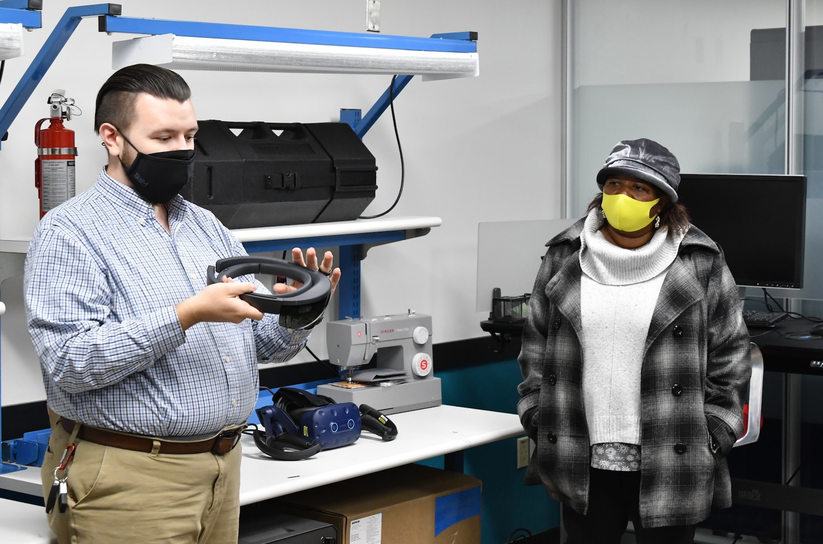 IMAGE: Michael Darnell (left), Innovation Lab engineer, explains a piece of virtual reality equipment to Andrea Clement, a member of the Colonial Beach town council in the Digital Warfare Innovation Center Lab as part of a tour with local elected officials. During their visit, the local officials received a briefing on multiple program areas and visited the Digital Warfare Innovation Center Lab and the laser lab.
