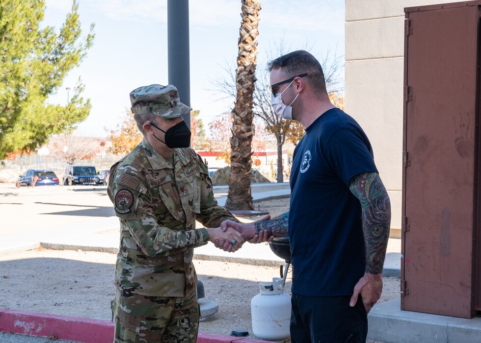 Col. Glenn Rineheart, Air Force Operational Test and Evaluation Center, Detachment 5 Commander, presents a coin to paramedic Staff Sgt. Christian Uttlinger at Edwards Air Force Base, California, Dec. 1. . (Air Force photo by Giancarlo Casem)