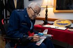 Man in motorized chair being given a tour by a pilot in military flight suit.