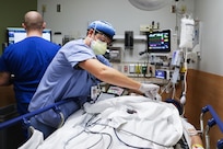 A male nurse wearing a face mask and gloves takes a patient’s blood.