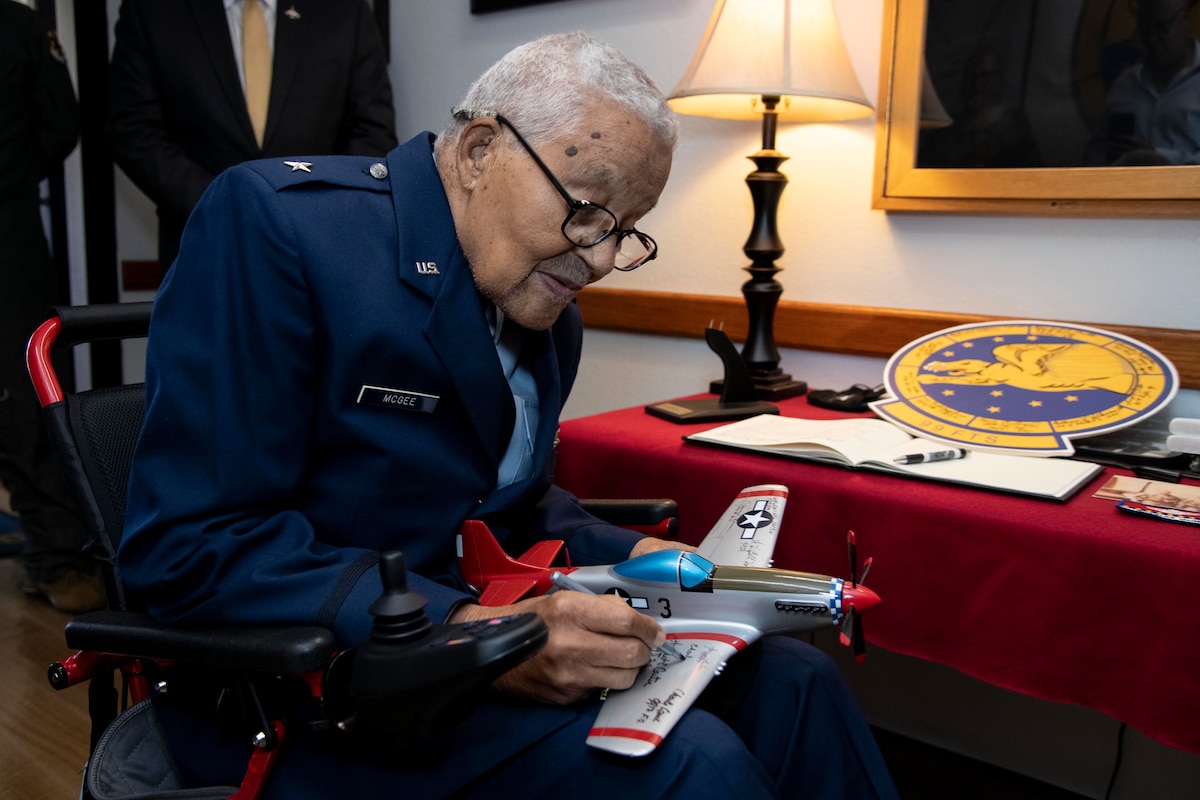 Retired Brig. Gen. Charles McGee, documented Tuskegee Airman, signs a P-51 Mustang model during his visit to the 99th Flying Training Squadron Dec. 6, 2021, at Joint Base San Antonio-Randolph, Texas. In celebration of the U.S. Air Force’s 75th anniversary, McGee was treated to a heritage tour of the 99th FTS and participated in a training mission in a T-1A Jayhawk aircraft simulator.