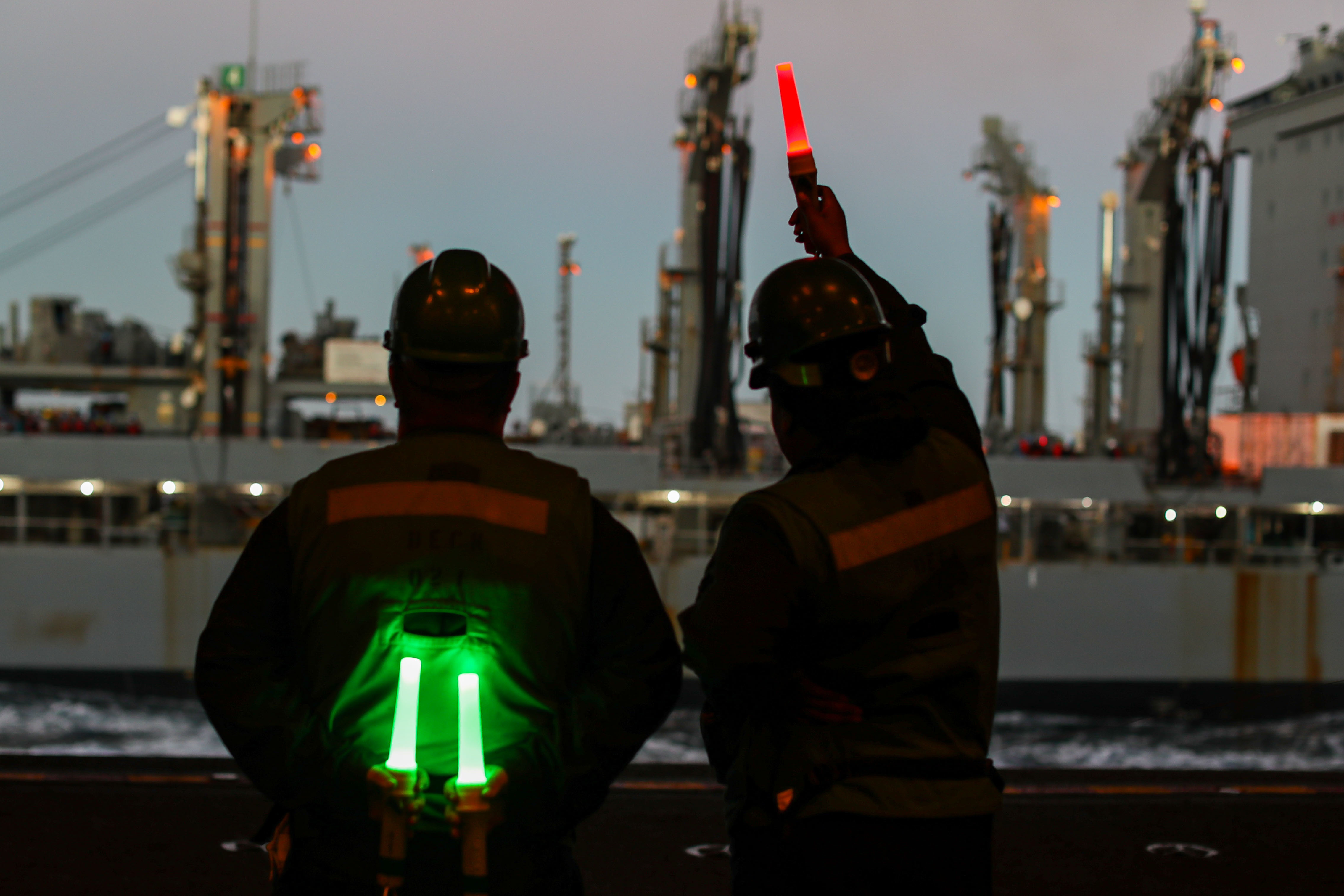 Seaman Courtney Maxis (right), from Richmond, Calif., signal the Military Sealift Command USNS Guadalupe (T-AO 200) in the hangar bay aboard USS Abraham Lincoln (CVN 72) during a replenishment-at-sea.