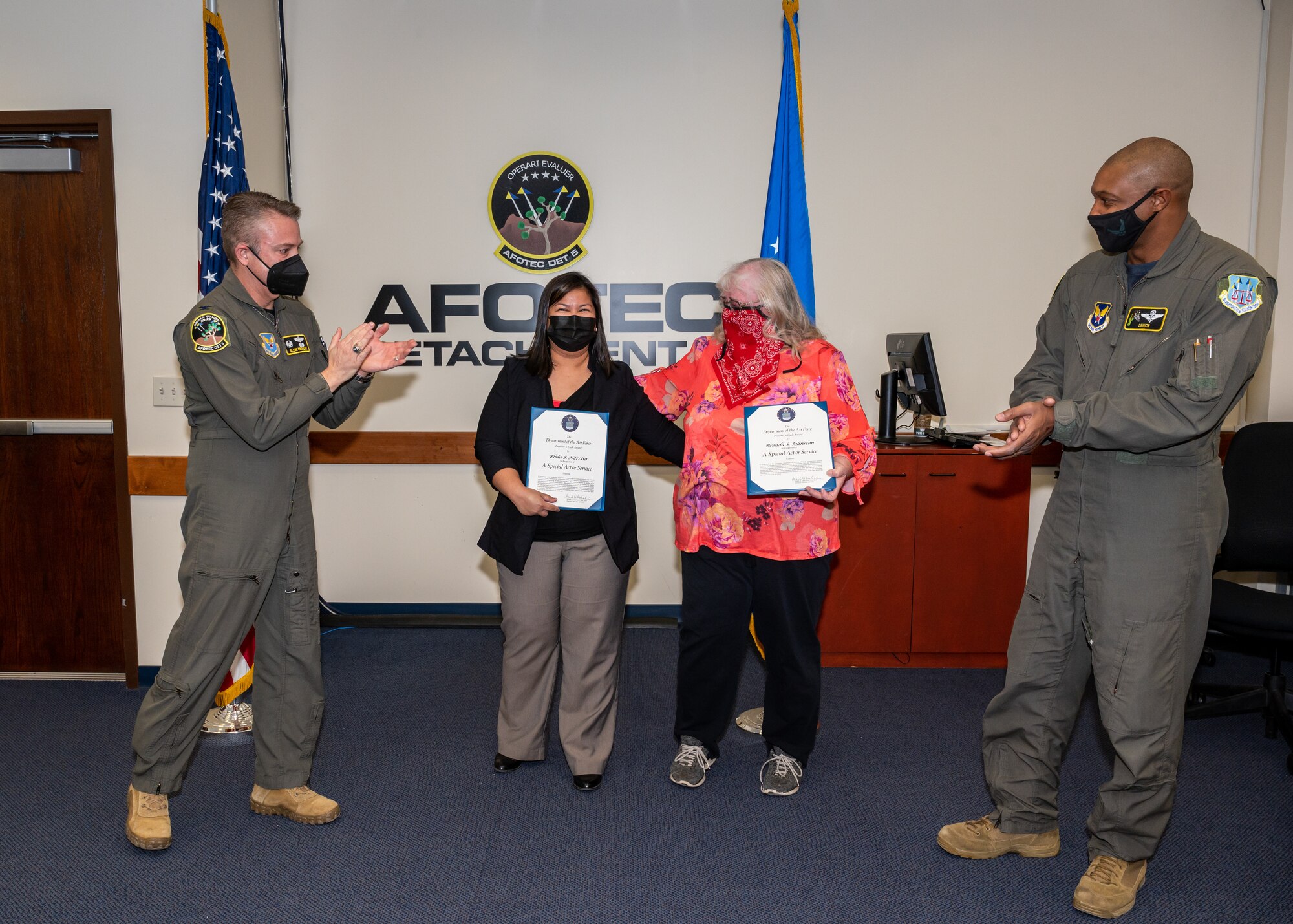 The Air Force Operational Test and Evaluation Center, Detachment 5, commander, Col. Glenn Rineheart, and senior enlisted leader, Senior Master Sgt. Brian Pettaway, congratulate teammates Elida Narciso and Brenda Johnston after receiving a special award for their actions resulting in saving a fellow team member's life, at Edwards Air Force Base, California, Dec. 3. (Air Force photo by Giancarlo Casem)