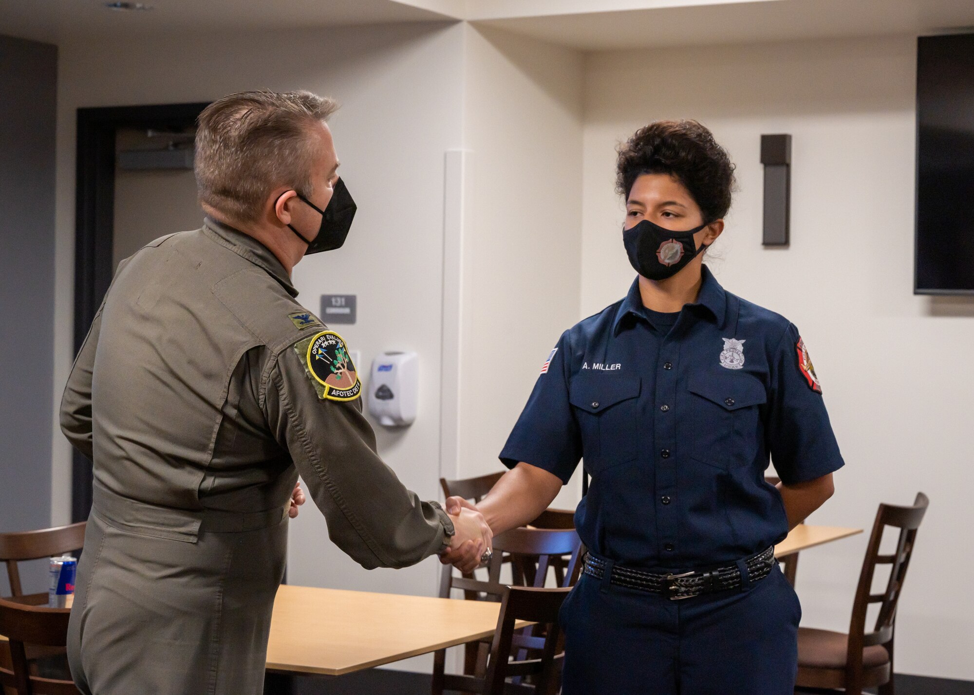 Col. Glenn Rineheart, Air Force Operational Test and Evaluation Center, Detachment 5 Commander, presents a coin to Emergency Medical Technician Alysha Miller at Edwards Air Force Base, California, Dec. 1. Miller and fellow EMTs were the first responders to a medical emergency involving an AFOTEC Det. 5 team member. Rineheart credits base emergency personnel for possibly saving the individual's life. (Air Force photo by Giancarlo Casem)