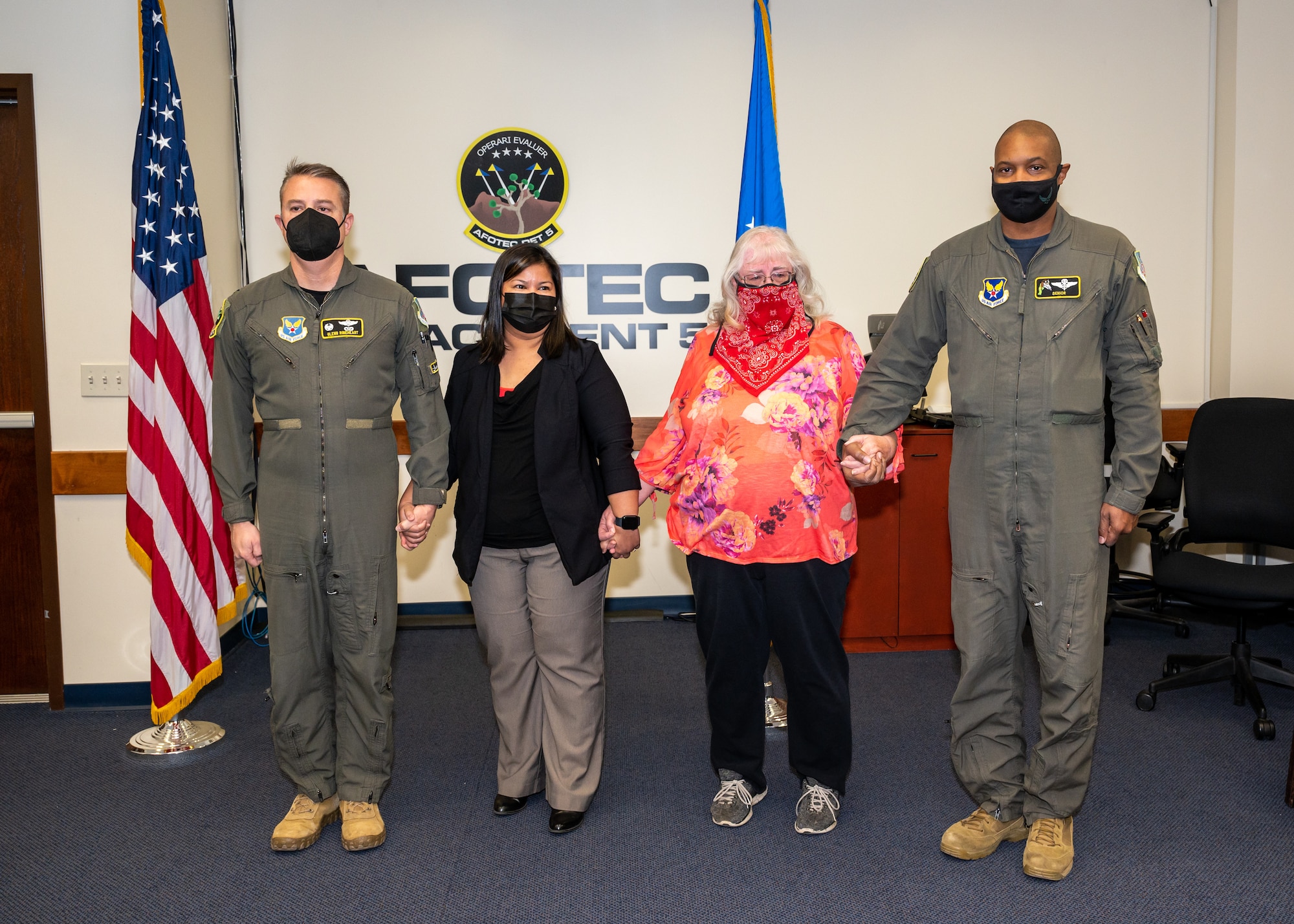 The Air Force Operational Test and Evaluation Center, Detachment 5, commander, Col. Glenn Rineheart, and senior enlisted leader, Senior Master Sgt. Brian Pettaway, hold hands with teammates Elida Narciso and Brenda Johnston while their citation is read at Edwards Air Force Base, California, Dec. 3. Narciso and Johnston each received a special award for their actions resulting in saving a fellow team member's life, (Air Force photo by Giancarlo Casem)