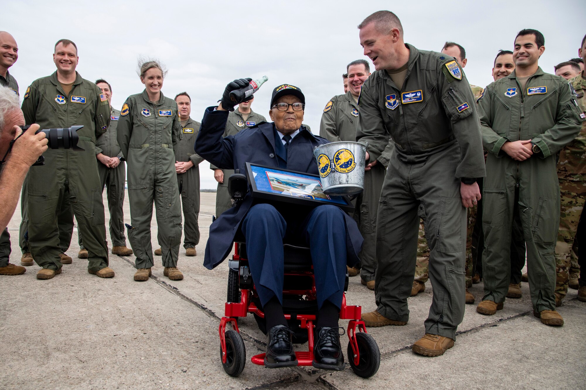 Retired Brig. Gen. Charles McGee, a documented Tuskegee Airman, holds up a bottle of cola to honor the tradition of shooting down an enemy aircraft during his tour of the 99th Flying Training Squadron Dec. 6, 2021, at Joint Base San Antonio, Texas. In celebration of the U.S. Air Force’s 75th anniversary, McGee was treated to a heritage tour of the 99th FTS and participated in a training mission in a T-1A Jayhawk aircraft simulator the day before his 102nd birthday.