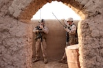 Two military personnel talk on hand-held radios.