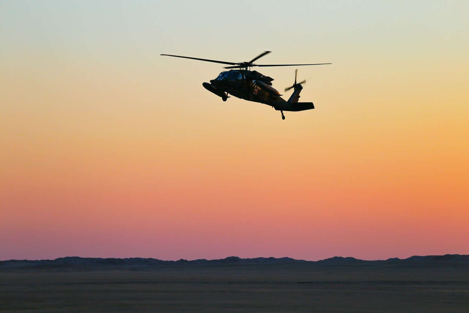 A helicopter flies above the desert.
