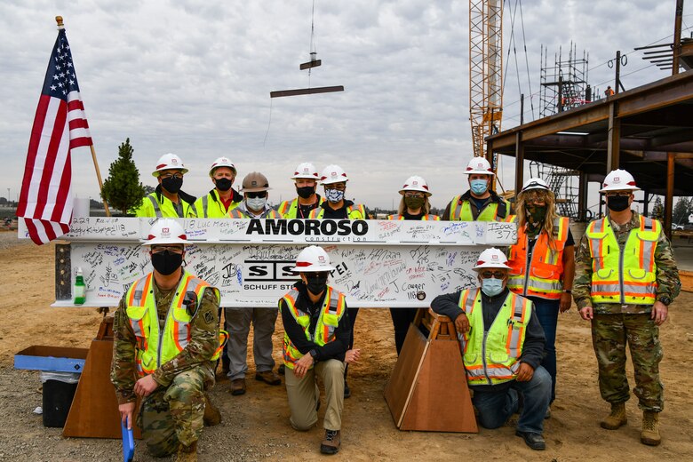 People pose for a picture with a beam of steel