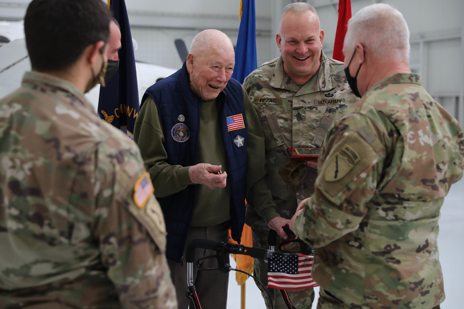 Sayre Christian Village resident Paul Frederick and Command Sgt. Maj. Paul Rezac, 63rd Theater Aviation Brigade, smile as Maj. Gen. Hal Lamberton, Kentucky National Guard adjutant general, presents Frederick and Soldiers with a military coin following a ceremony at the Army Aviation Support Facility hangar at Boone National Guard Center Dec. 2.