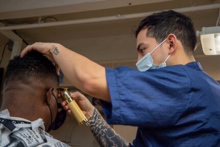 Retail Service Specialist 3rd Class David Nieto, from McAllen, Texas, cuts a Sailor's hair in the barbershop aboard the Nimitz-class aircraft carrier USS Harry S. Truman (CVN 75).