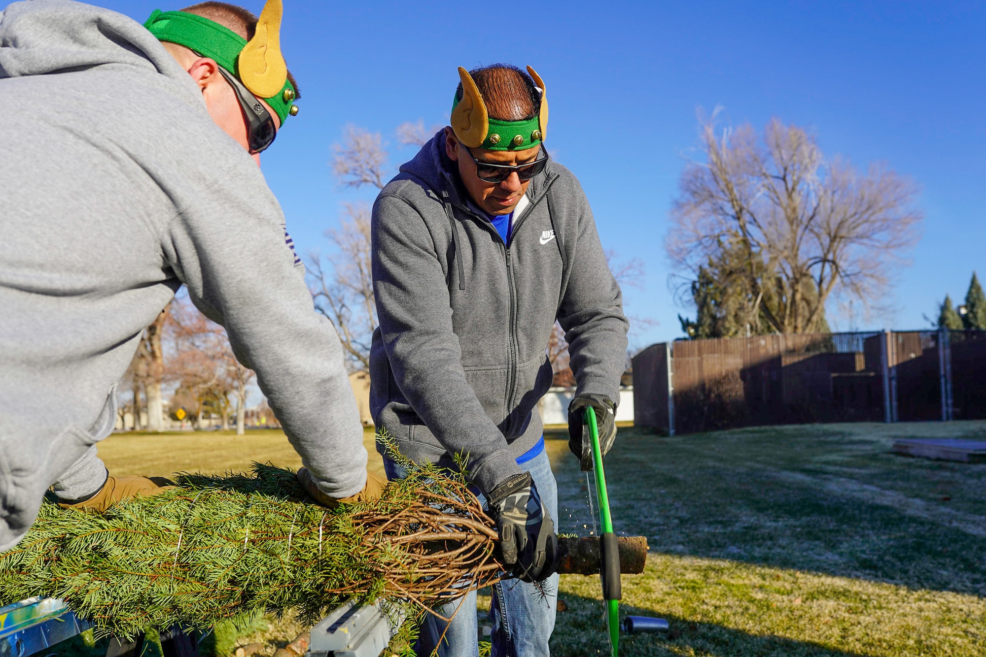 From left, Master Sgt. Randy Hassenplug, 75th Force Support Squadron first sergeant, and Senior Master Sgt. Jason Dela Cruz, 75th Security Forces Squadron first sergeant, cut the bottom off of a Christmas tree at Hill Air Force Base, Utah, Dec. 4, 2021. Trees for Troops, a program of the Christmas SPIRIT Foundation, provided live Christmas trees to 150 service members and their families with the help of volunteers from Hill AFB. (U.S. Air Force photo by 2nd Lt. Taylor Ferry)