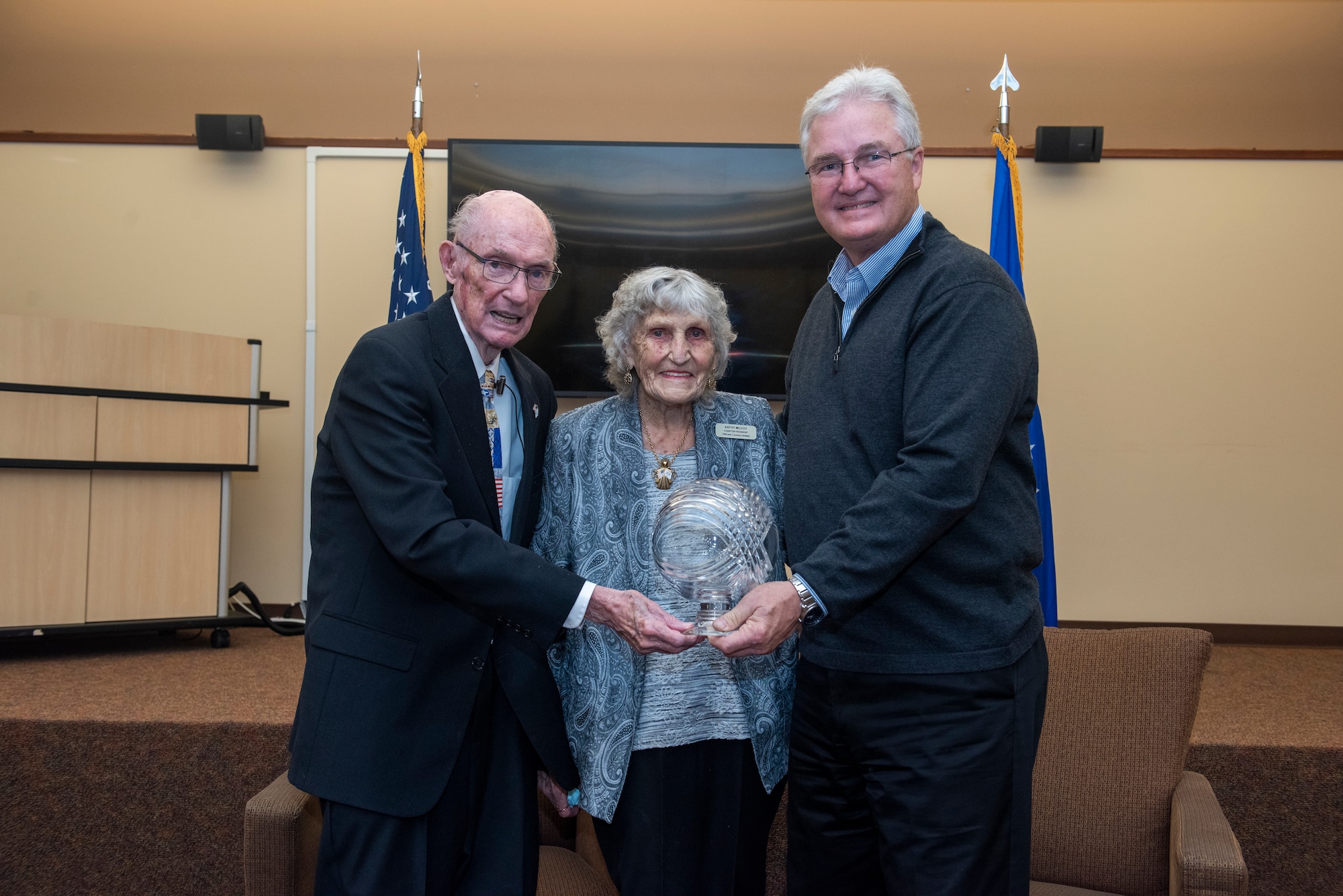 The sixth Chief Master Sergeant of the Air Force receives an award from the 14th Chief Master Sergeant of the Air Force as the The sixth Chief Master Sergeant of the Air Force's wife stands in the middle.