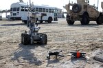 A robot operated by the Explosive Ordnance Disposal team approaches two downed Unmanned Aerial Systems, armed with a simulated explosive device, during an exercise at Al Dhafra Air Base, United Arab Emirates, Dec. 3, 2021. The 380th Expeditionary Security Forces Squadron at the base has responsibility for countering potential UAS threats. (U.S. Air Force photo by Master Sgt. Dan Heaton)