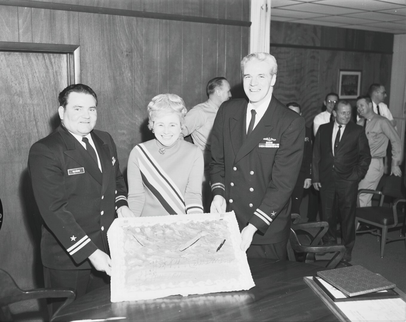 Lt. Milhorn Retirement: A Service to the Fleet historic photograph shows Lt. Harvey H. Milhorn (left) and Lt. Arthur P. Murray (right), former ships superintendents at Norfolk Naval Shipyard (NNSY), displaying a cake presented to them following their retirement ceremony in February 1970.