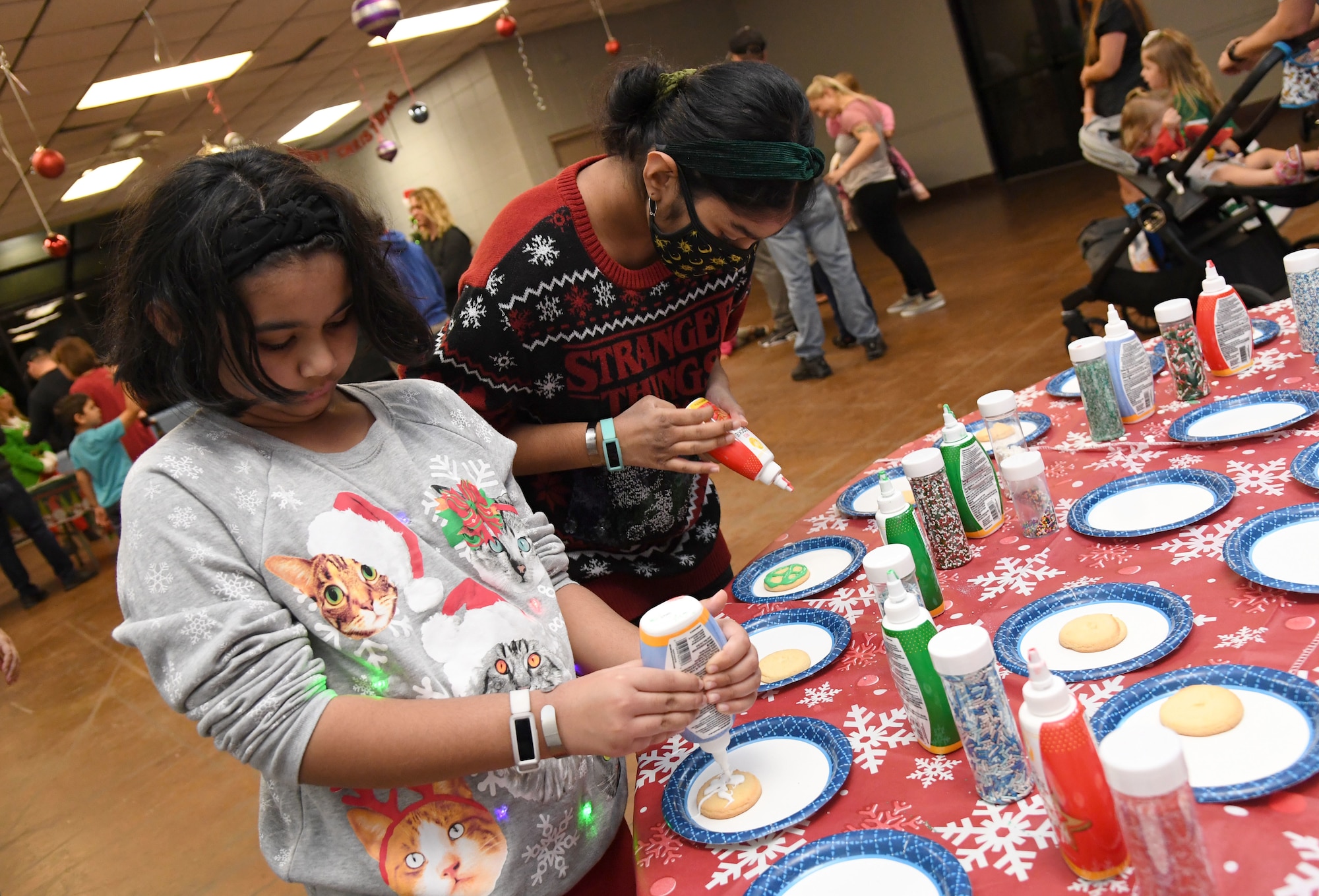 Ayesha and Aasiya Akbar, daughters of U.S. Navy Lt. Mohammed Akbar, Naval Construction Group TWO civil engineer, Naval Construction Battalion Center, Gulfport, Mississippi, decorate cookies during the 2021 Winter Fest at the marina park on Keesler Air Force Base, Mississippi, Dec. 3, 2021. The event, which included a visit with Santa and a tree lighting ceremony, was held in celebration of the holiday season. (U.S. Air Force photo by Kemberly Groue)