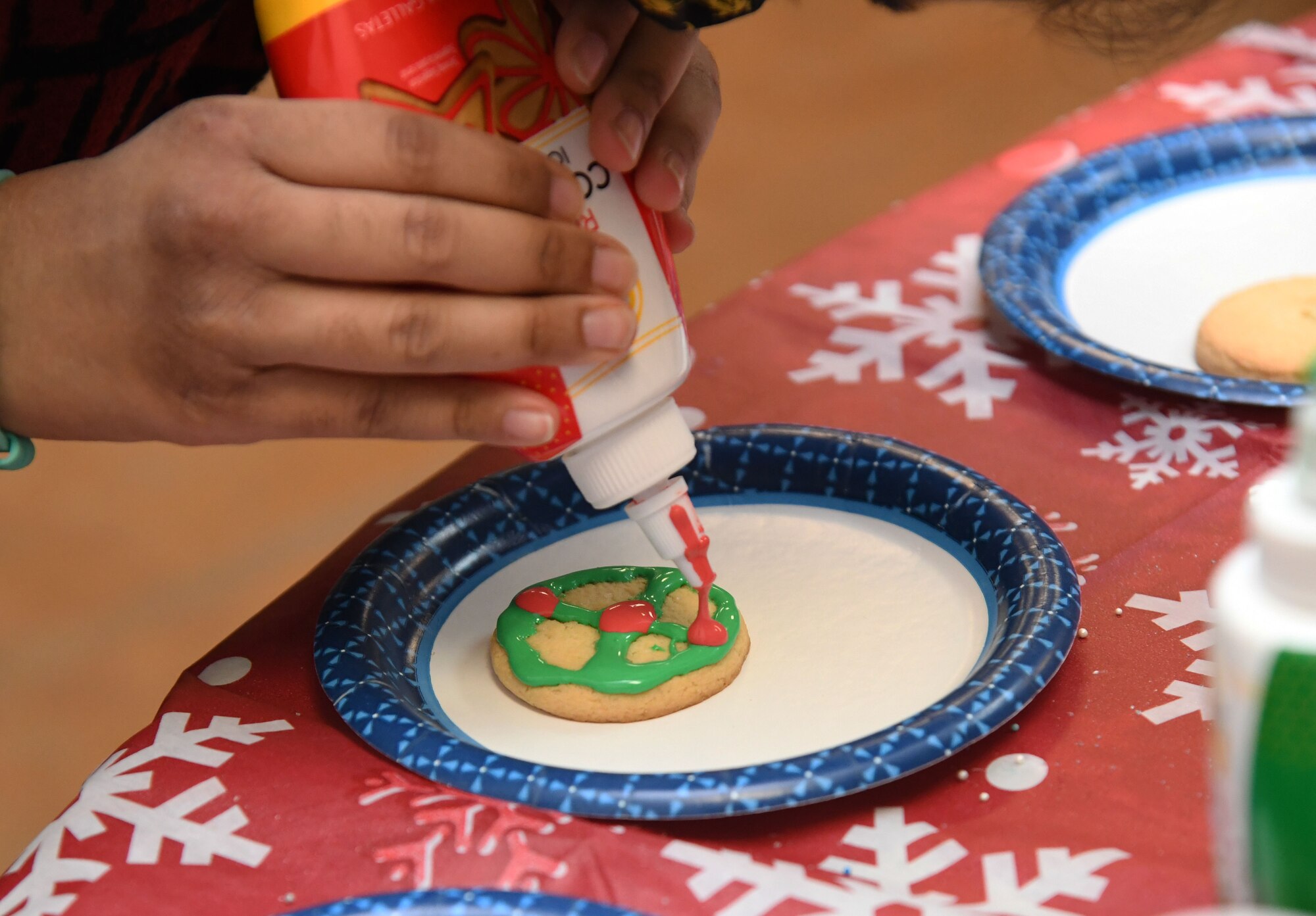 Aasiya Akbar, daughter of U.S. Navy Lt. Mohammed Akbar, Naval Construction Group TWO civil engineer, Naval Construction Battalion Center, Gulfport, Mississippi, decorates a cookie during the 2021 Winter Fest at the marina park on Keesler Air Force Base, Mississippi, Dec. 3, 2021. The event, which included a visit with Santa and a tree lighting ceremony, was held in celebration of the holiday season. (U.S. Air Force photo by Kemberly Groue)