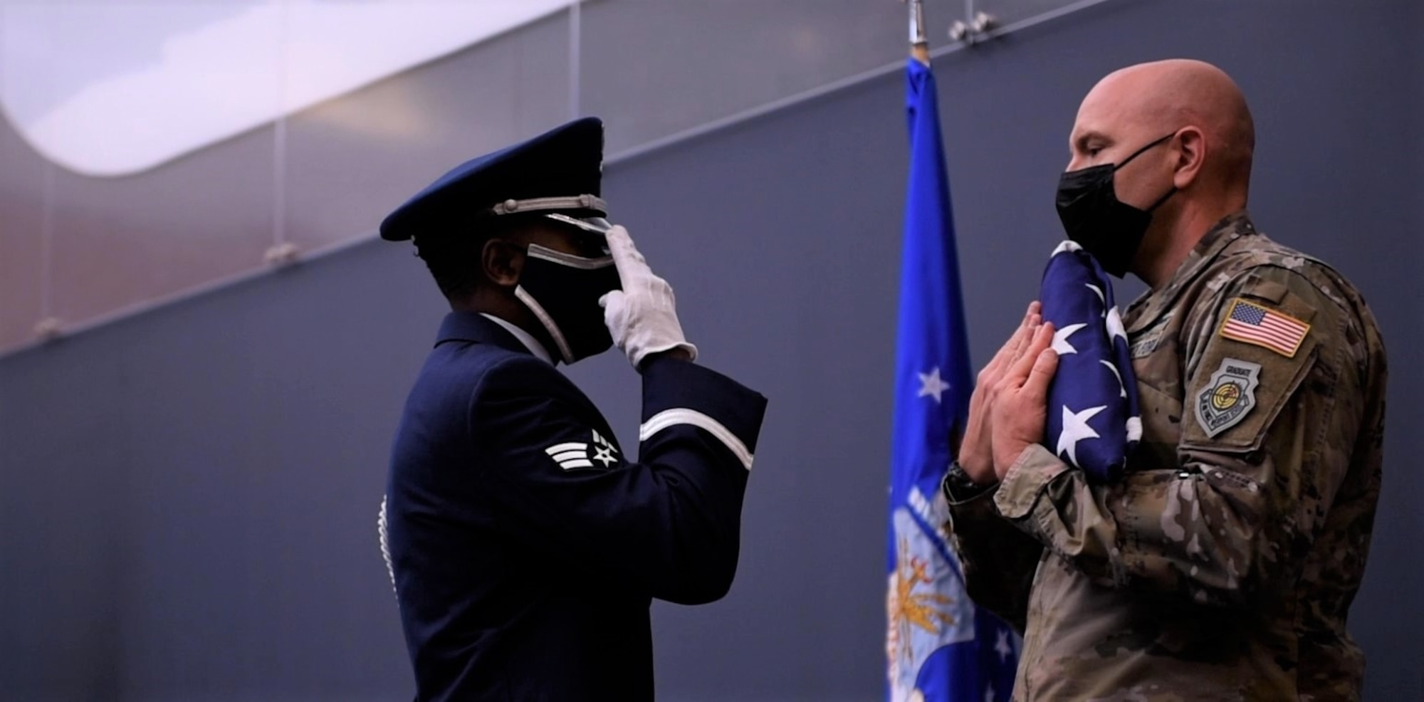Col. Fernengel holds A flag while an air force honor guardsman salutes.