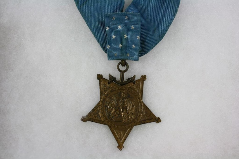 A five-point medal is attached to a blue ribbon.