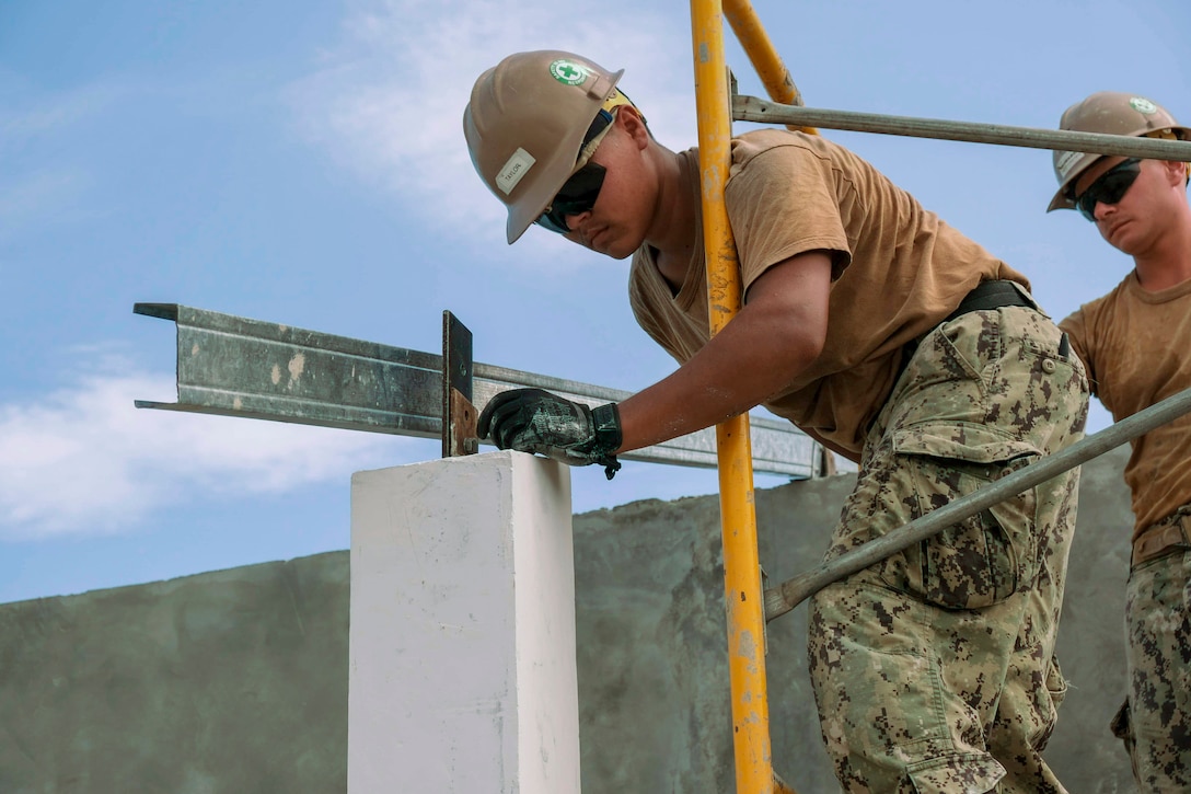A Navy Seabee works to secure a truss.