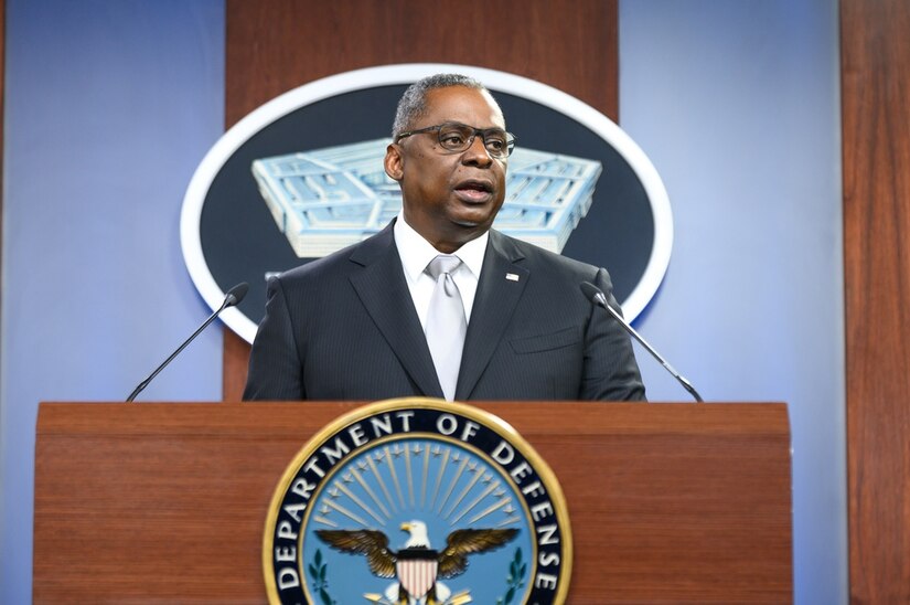 A man stands at a lectern. The sign behind him indicates he is at the Pentagon.